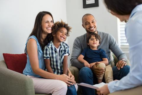A family with two young children talks to a counselor 